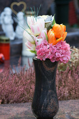 brightly colored artificial flowers on a grave against blurred background