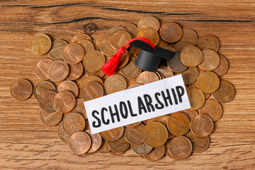 Paper with word Scholarship, graduation cap and coins on wooden table, flat lay