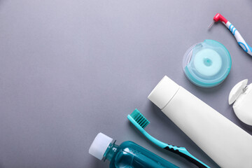 Flat lay composition with dental floss and different teeth care products on grey background. Space...