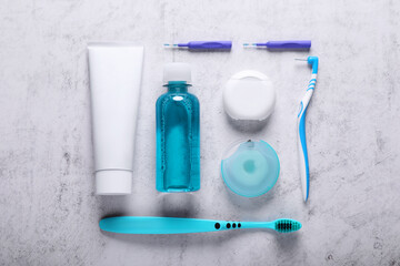 Flat lay composition with dental floss and different teeth care products on light grey textured table