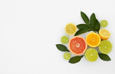 Different citrus fruits and leaves on white background, top view