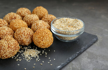 Delicious sesame balls and seeds on grey table