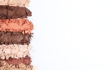 Swatches of crushed eye shadows on white background, top view. Space for text
