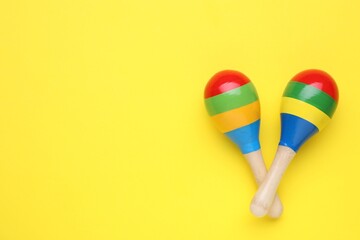 Colorful maracas on yellow background, flat lay with space for text. Musical instrument