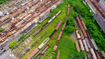 abandoned train station and wagon, with forest covering part of them. Aerial view on the city of...