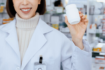 Closeup young affable pharmacist show qualified medicine pill bottle mockup product for copyspace...