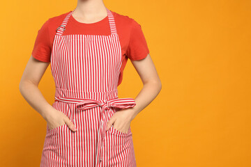Woman in clean striped apron on orange background, closeup