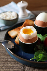 Delicious breakfast with soft boiled eggs served on wooden table, closeup
