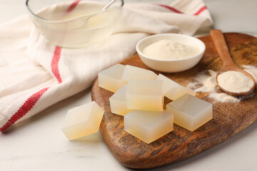 Agar-agar jelly cubes and powder on white marble table, closeup