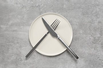 Clean plate with shiny silver cutlery on light grey table, flat lay