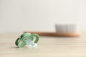 Baby pacifiers on beige table against blurred background, space for text