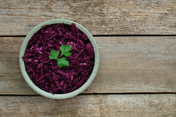Tasty red cabbage sauerkraut with parsley on wooden table, top view. Space for text