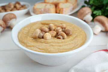 Delicious mushroom cream soup on white wooden table