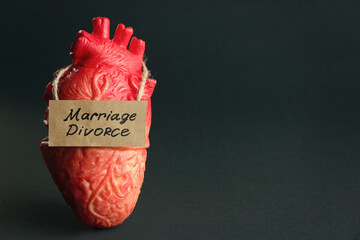 Model of heart and card with words Marriage Divorce on black background. Space for text