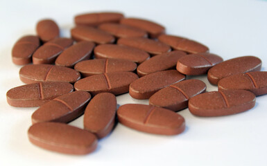 Close up of brown vitamin pills on a white background