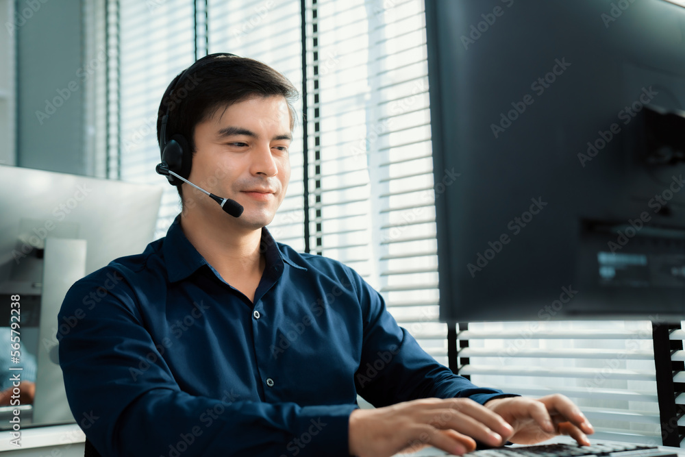 Aufkleber young competent asian male call center agent working at his computer while simultaneously speaking w