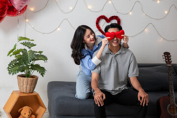 Couple in love holding red heart-shaped cards and smiling happy in Valentine's Day concept.