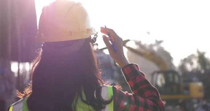 Worker with uniform on construction site against sunset background, worker or engineer with helmet