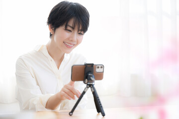 スマホで撮影したり動画配信をする可愛いらしい女性　春っぽいイメージ