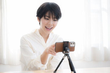 Cute Asian woman taking pictures and streaming video on her phone.