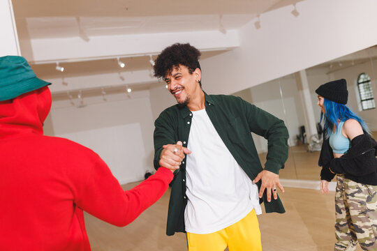 Image of happy diverse male hip hip dancers shaking hands in studio