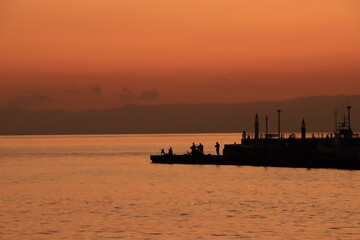 Fototapeta premium 漁港にある防波堤で釣りをする人のシルエットの夕景