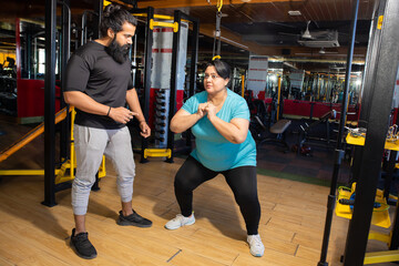 Young overweight indian woman workout in gym with trainer to lose weight and burn belly fat exercise. fitness and health care