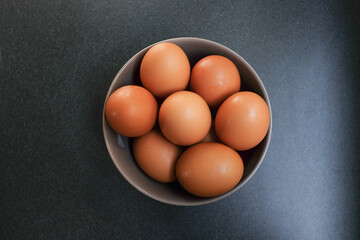 Top view of eggs in bowl on dark background.