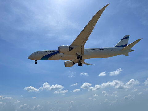 Airplane Boeing 787-8 close-up in the sky in flight. Released chassis. Plane just took off. Aircraft is landing. Dreamliner in the skies. Beautiful shaped white clouds surround large liner. Sun shines