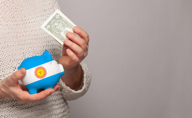 Flag of Argentina on money bank in Argentine woman hands. Dotations, pension fund, poverty, wealth, retirement concept