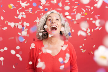 Cheerful mature woman surrounded by confetti in the air
