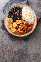 Pabellon criollo is a traditional Venezuelan dish made with shredded beef that is typically served with white rice, black beans and fried plantains closeup on the plate on the table. Vertical top view