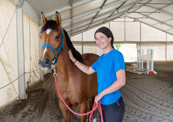 Happy young woman petting horse