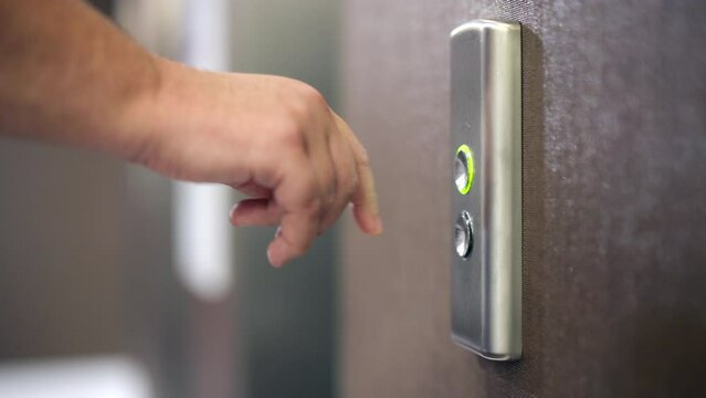 Detailed view of a man pressing a call button in an apartment building. Close-up shot of a passenger waiting for the cabin for upwards transportation. High quality 4k footage