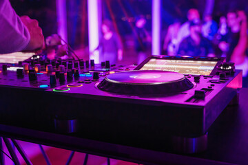 Close-up of a DJ booth at a nightclub, with the focus on one of the turntables and the colorful...