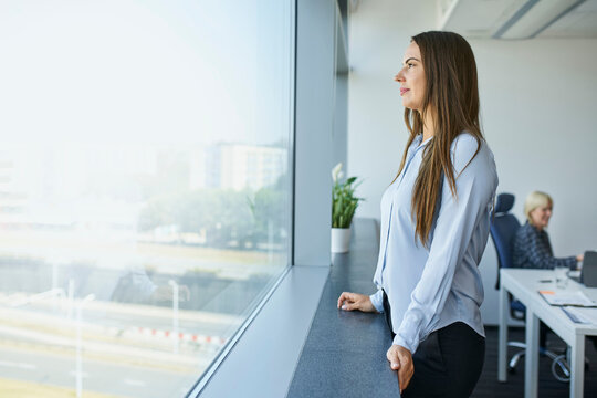 Businesswoman standing in office looking through the window