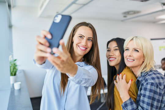 Team of women taking selfie at office