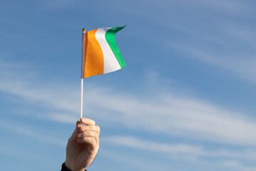 Republic of Côte d'Ivoire flag in hand flutters in the wind against the sky
