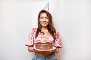 The girl is holding a festive cake with a candle in the form of the number 19. The concept of a...