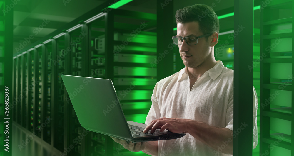 Poster man employee of data center. guy with laptop near server equipment. big data specialist. data center