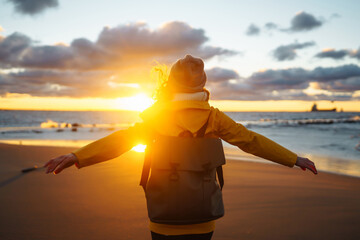 Happy tourist in a yellow jacket enjoying sea landscape at sunset. Lifestyle, travel, tourism, nature, active life.