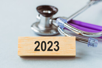 Changes in health care in year 2023. Stethoscope and numbers 2022 and 2023 on wooden cubes on blue...
