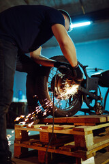 Motorcycle repair. Disassembled motorcycle. The expert works with electric welding of metal. Instruments and equipment.