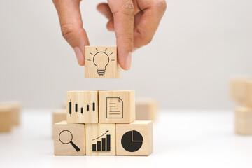 Hand holding a wooden block cube the top one with light bulb icon symbol. Target of business and innovative idea concept.