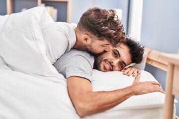 Young couple hugging each other and kissing lying on bed at bedrooom