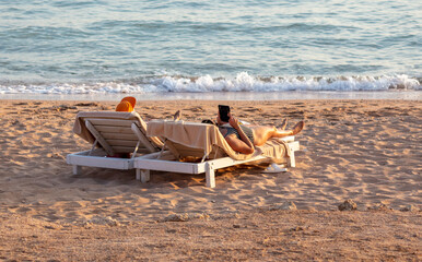 Fototapeta na wymiar A man with a girl on deck chairs by the sea at sunset.