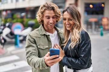 Man and woman couple smiling confident using smartphone at street