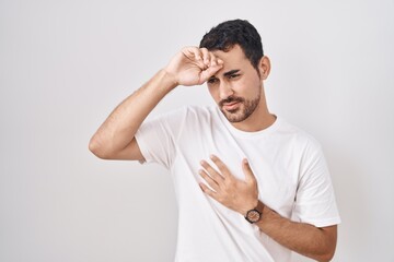 Handsome hispanic man standing over white background touching forehead for illness and fever, flu and cold, virus sick