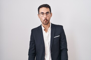 Handsome business hispanic man standing over white background making fish face with lips, crazy and comical gesture. funny expression.