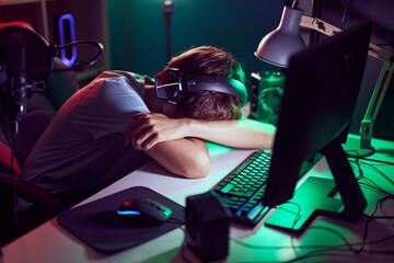 Fototapeta na wymiar Young blond man streamer stressed using computer at gaming room